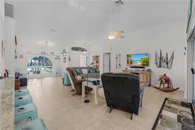 tiled living room with ceiling fan and a high ceiling