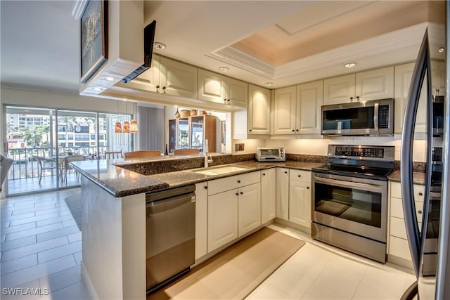 kitchen with black appliances, white cabinetry, dark stone countertops, kitchen peninsula, and a raised ceiling