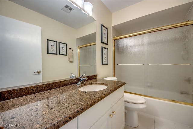 full bathroom with vanity, bath / shower combo with glass door, tile patterned floors, and toilet