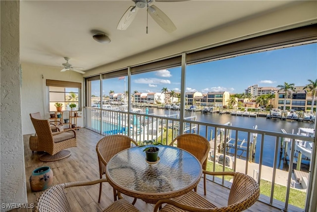 sunroom featuring a water view and ceiling fan