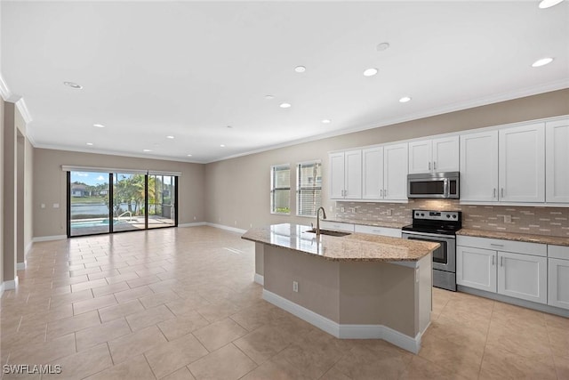 kitchen featuring stainless steel appliances, a sink, backsplash, and a center island with sink