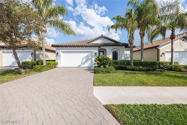 mediterranean / spanish house featuring decorative driveway, an attached garage, a tile roof, and stucco siding