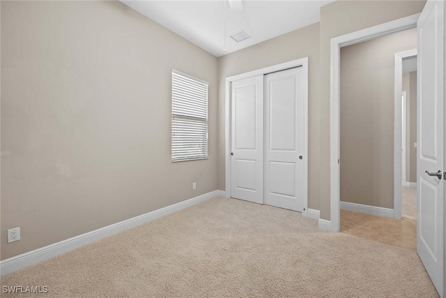 unfurnished bedroom with baseboards, a closet, and light colored carpet