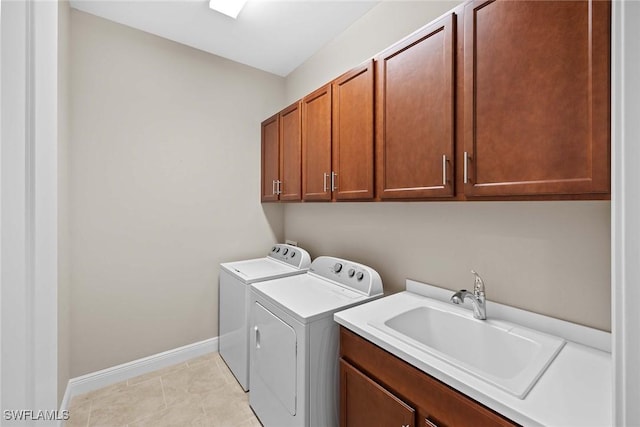 washroom with cabinet space, light tile patterned floors, baseboards, washer and dryer, and a sink