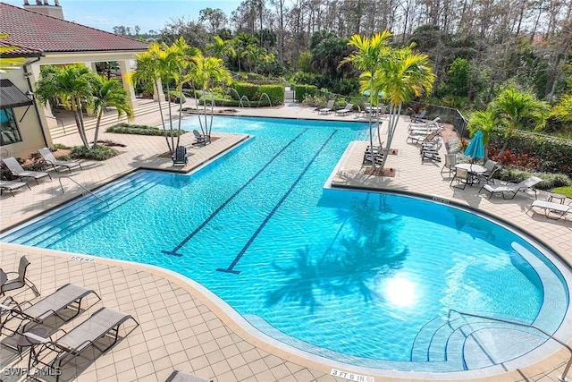 community pool with a patio area and fence