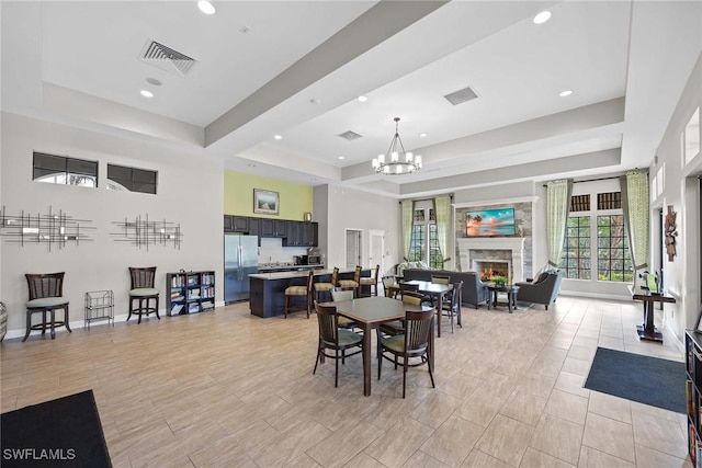 dining area featuring a warm lit fireplace, a raised ceiling, and visible vents