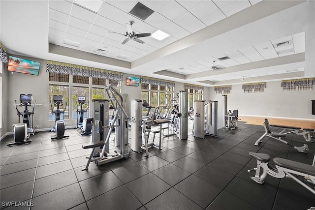 workout area featuring plenty of natural light, a tray ceiling, and a ceiling fan