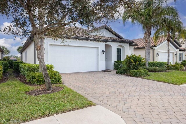 mediterranean / spanish house featuring a garage and a front lawn