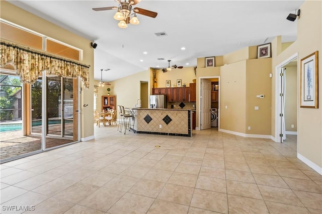 unfurnished living room featuring ceiling fan, lofted ceiling, washer / dryer, and light tile patterned floors