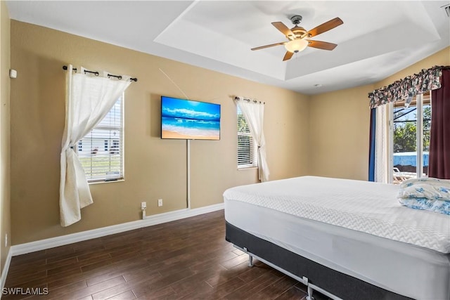 bedroom with a raised ceiling, ceiling fan, and dark hardwood / wood-style flooring