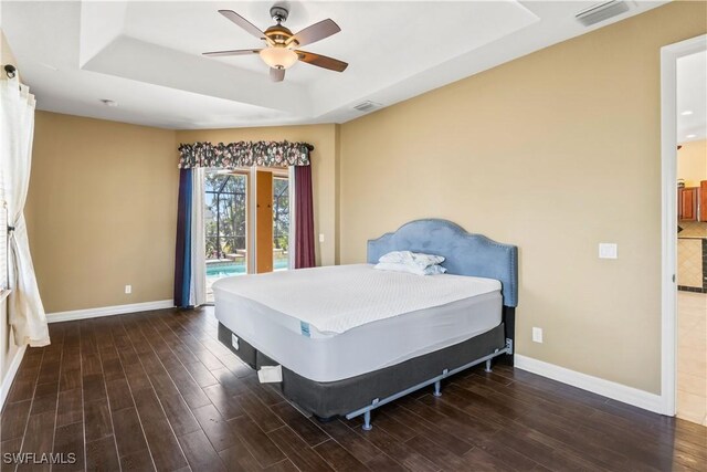 bedroom featuring dark wood-type flooring, ceiling fan, a raised ceiling, and access to outside