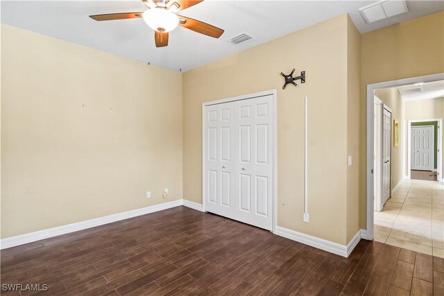 unfurnished bedroom with dark wood-type flooring, ceiling fan, and a closet