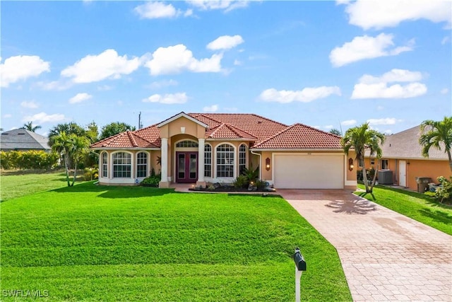 mediterranean / spanish home with cooling unit, a garage, and a front lawn