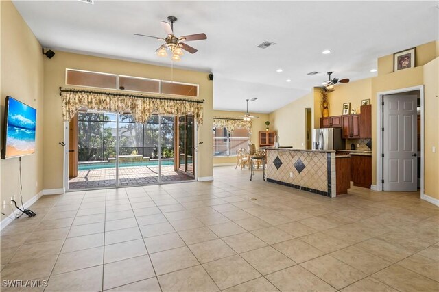 kitchen featuring stainless steel refrigerator with ice dispenser, a breakfast bar area, light tile patterned floors, pendant lighting, and ceiling fan