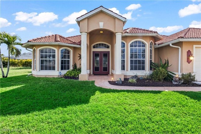 exterior space featuring a garage, a yard, and french doors