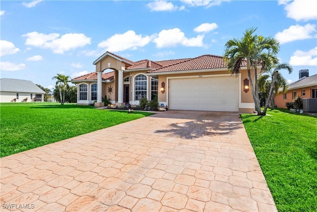 mediterranean / spanish home with a garage, a front lawn, and central air condition unit