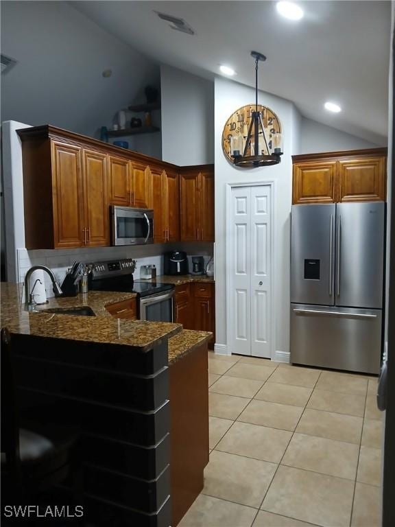 kitchen featuring sink, appliances with stainless steel finishes, hanging light fixtures, light tile patterned flooring, and dark stone counters