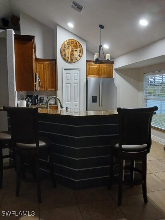 kitchen with stainless steel appliances, vaulted ceiling, light tile patterned floors, and kitchen peninsula