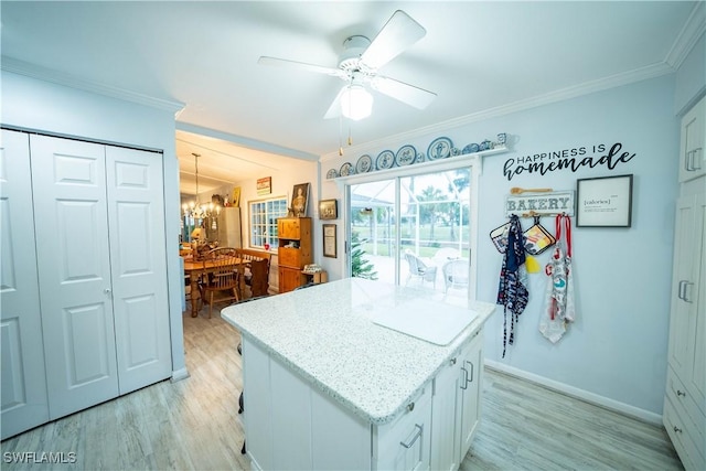 kitchen featuring ornamental molding, a center island, white cabinets, and light hardwood / wood-style flooring