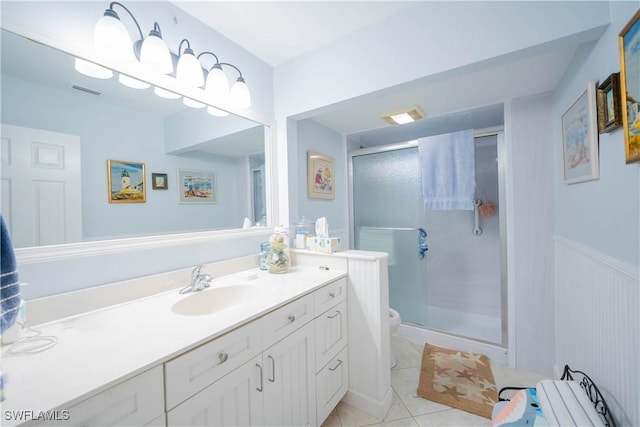 bathroom with toilet, vanity, tile patterned floors, and a shower with shower door