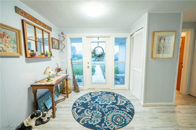 entryway with ornamental molding and hardwood / wood-style floors