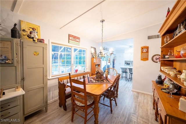 dining area with an inviting chandelier, vaulted ceiling, and light hardwood / wood-style floors