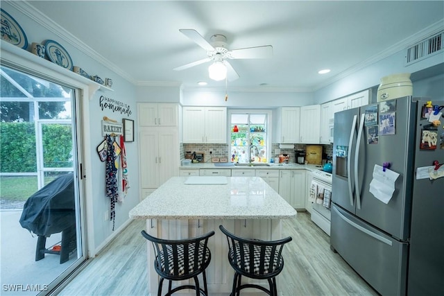 kitchen with white cabinetry, ornamental molding, stove, stainless steel refrigerator with ice dispenser, and light stone countertops