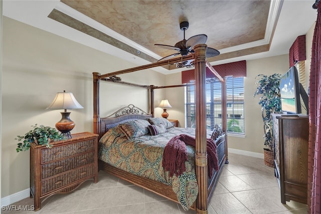 bedroom with a raised ceiling, light tile patterned floors, and ceiling fan