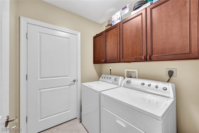 laundry room with cabinets, light tile patterned floors, and washer and dryer