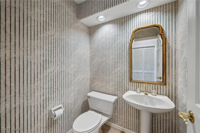 bathroom with recessed lighting, a sink, toilet, and wallpapered walls