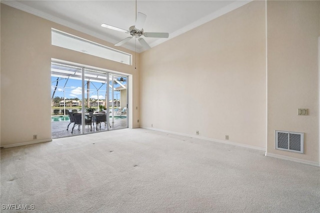 carpeted empty room featuring a high ceiling, crown molding, ceiling fan, and a water view