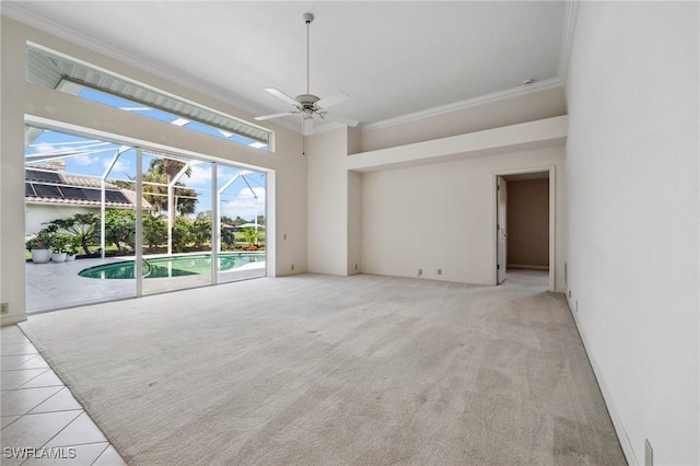 empty room featuring light tile patterned flooring, a sunroom, a towering ceiling, a ceiling fan, and ornamental molding