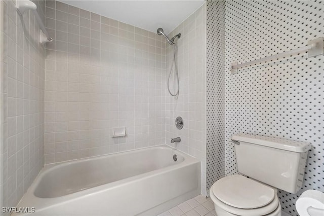 bathroom featuring tile patterned flooring, tiled shower / bath combo, and toilet