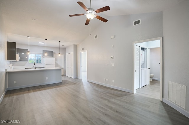 unfurnished living room with ceiling fan, sink, high vaulted ceiling, and light hardwood / wood-style flooring