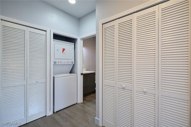 laundry area with stacked washer and clothes dryer and light hardwood / wood-style flooring