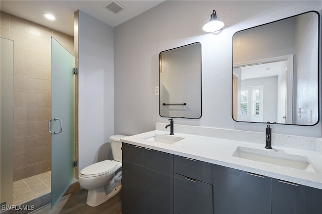 bathroom with vanity, a shower with door, and toilet