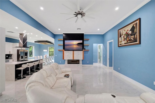 living room featuring crown molding, ceiling fan, and a fireplace