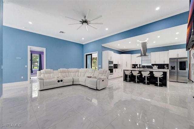 living room featuring crown molding, sink, and ceiling fan