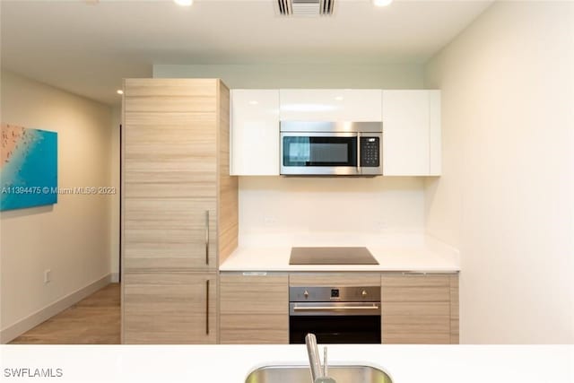 kitchen with sink, light brown cabinets, white cabinets, and appliances with stainless steel finishes