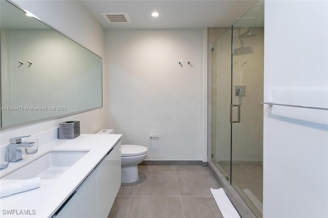 bathroom with tile patterned floors, toilet, a shower with door, and vanity