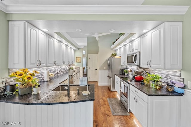 kitchen featuring light hardwood / wood-style flooring, backsplash, stainless steel appliances, white cabinets, and kitchen peninsula