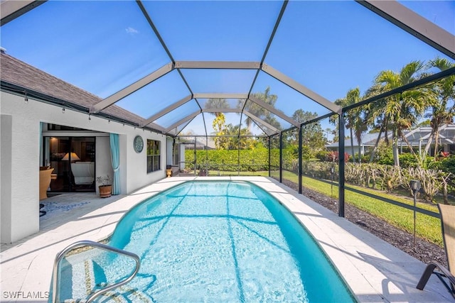 view of pool with glass enclosure and a patio area