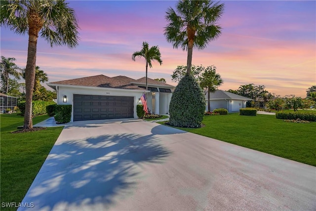 ranch-style home featuring a garage and a yard