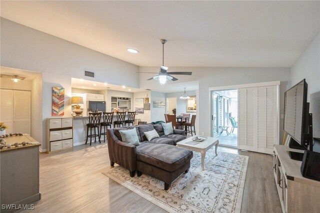 living room featuring high vaulted ceiling, light hardwood / wood-style floors, and ceiling fan