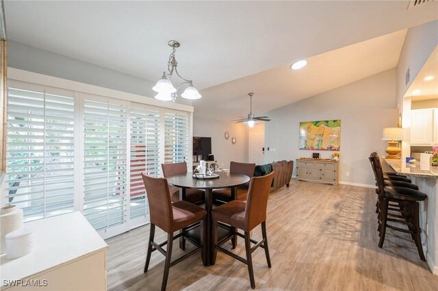 dining area featuring vaulted ceiling, ceiling fan with notable chandelier, and light wood-type flooring