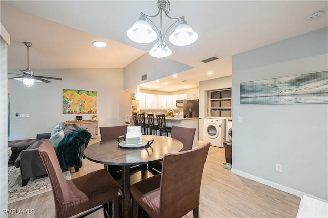 dining space with separate washer and dryer, ceiling fan with notable chandelier, light hardwood / wood-style floors, and lofted ceiling