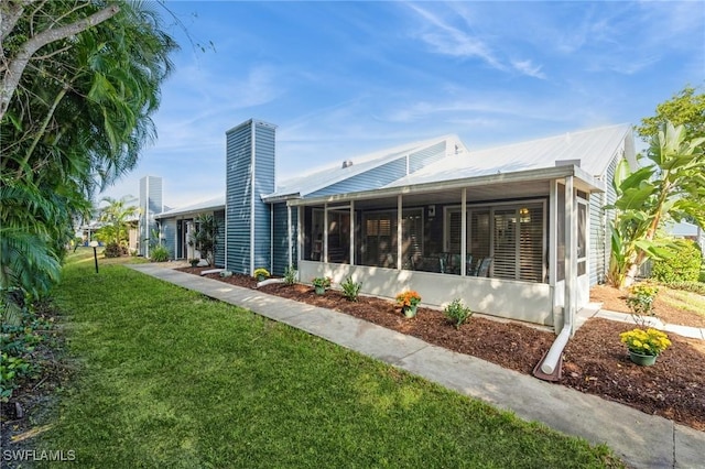 back of property with a sunroom and a lawn