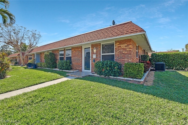 ranch-style home featuring cooling unit and a front yard