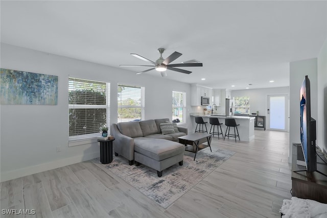 living room with ceiling fan and light wood-type flooring