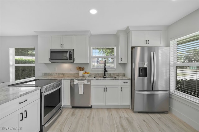 kitchen featuring sink, white cabinetry, plenty of natural light, stainless steel appliances, and light stone counters